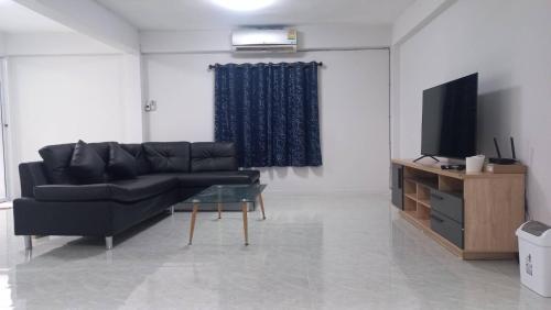 a living room with a black couch and a television at CG BNB HOTEL in Chiang Mai