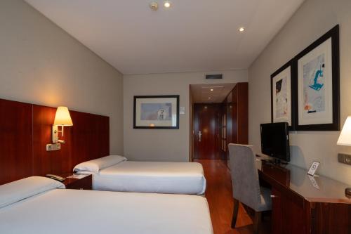 a hotel room with two beds and a desk at Hotel Attica21 Las Rozas in Las Rozas de Madrid