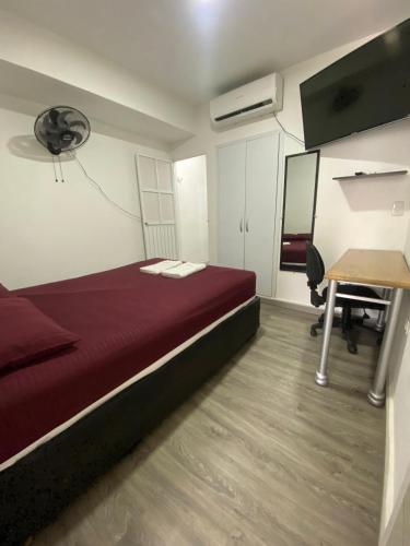 1 dormitorio con cama roja, escritorio y escritorio en Apartamento, en Cartagena de Indias