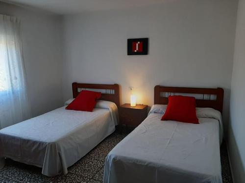 2 łóżka z czerwonymi poduszkami w pokoju w obiekcie Casa rural con barbacoa y amplia terraza. w mieście Jorquera