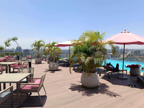 a patio with tables and palm trees and a pool at Skynest Residences by Lisa's Paradise E in Nairobi