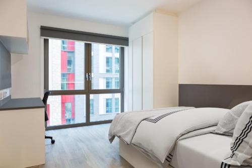 a white bedroom with a bed and a large window at For Students Only Chic Studios and Ensuites at Chapter Highbury II in London in London