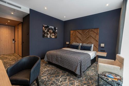 a bedroom with a king sized bed and a chair at Van Der Valk Hotel Almere in Almere