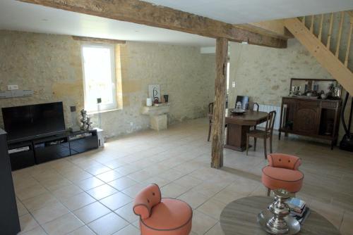 un salon avec des chaises orange et une télévision dans l'établissement La Parenthèse Girondine, à Pujols Gironde