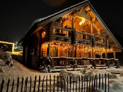 ゴスラーにあるHahnenkleer Hütteの雪中のクリスマスライトで覆われたログキャビン