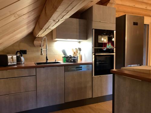 eine Küche mit Küchengeräten aus Edelstahl und Holzdecken in der Unterkunft Hahnenkleer Hütte in Goslar
