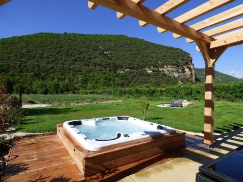 a hot tub on a wooden deck with a pergola at Camin'hôtes Gîte Spa Drôme Lavande in Béconne