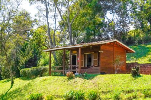 a small wooden cabin on a grassy hill at VELINN Hotel Fazenda Fonte das Hortênsias in Santo Antônio do Pinhal