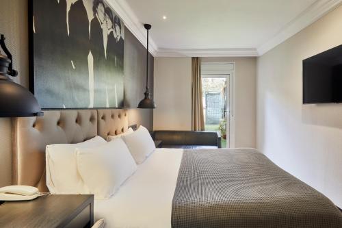 a bedroom with a bed and a desk and a television at Hotel Cortes Rambla in Barcelona