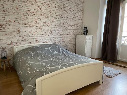 Ce lit se trouve dans une chambre dotée d'un mur en briques. dans l'établissement Dol de Bretagne : Appartement en plein centre, à Dol-de-Bretagne