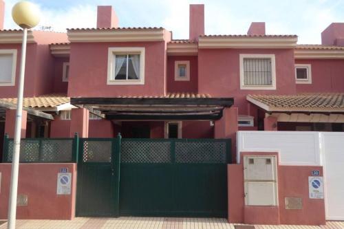 a red house with a green gate in front of it at Casa Atalanta - huis met zwembad in Albatros 2 in Mar de Cristal