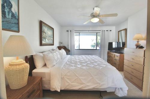 a bedroom with a white bed and a ceiling fan at Beachside Golf Villa in Fort Pierce