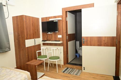 Pokój z łóżkiem, 2 krzesłami i telewizorem w obiekcie Green park w mieście Waranasi