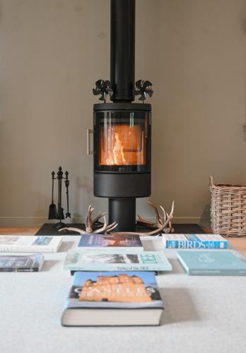 a stove with books on a table with a fireplace at Greenwood - Stunning Scandinavian Style Home in the heart of Ballater Royal Deeside in Ballater