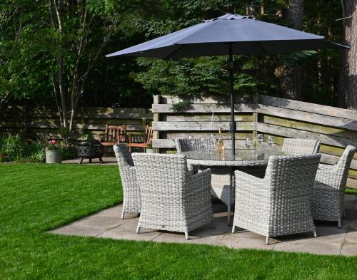 a table and chairs with an umbrella in a yard at Greenwood - Stunning Scandinavian Style Home in the heart of Ballater Royal Deeside in Ballater