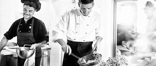 two men standing in a kitchen preparing food at Agriturismo Gattogiallo in Montegabbione