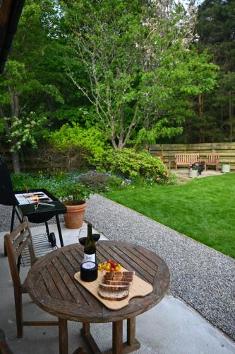 a table with a bottle of wine and a basket of fruit at Greenwood - Stunning Scandinavian Style Home in the heart of Ballater Royal Deeside in Ballater