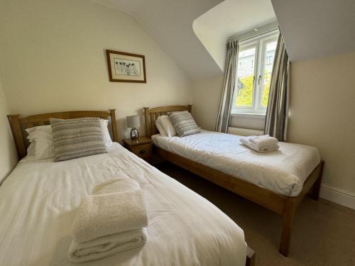 two beds in a room with a window at Damson Cottage - Peaceful location, charming communal orchard & private patio garden in Dittisham