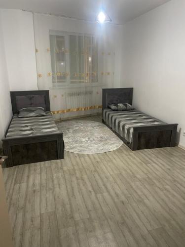 two beds in a room with wooden floors at Жана кала, 11-ая улица, 3-х комнатная квартира in Tridtsatʼ Let Kazakhstana