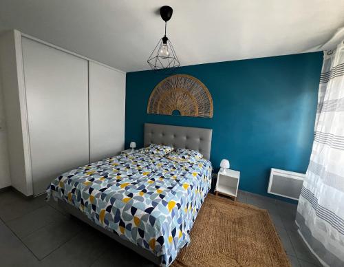 een slaapkamer met een bed met een blauwe muur bij Douceur en Ville Saint Raphel in Saint-Raphaël