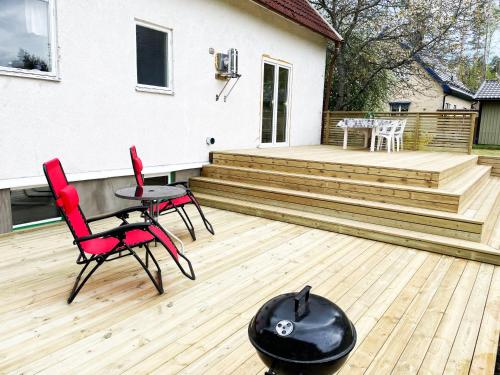 una terraza con 2 sillas, una mesa y un casco negro en Villa with 4 bed rooms with internet in Vimmerby en Gullringen