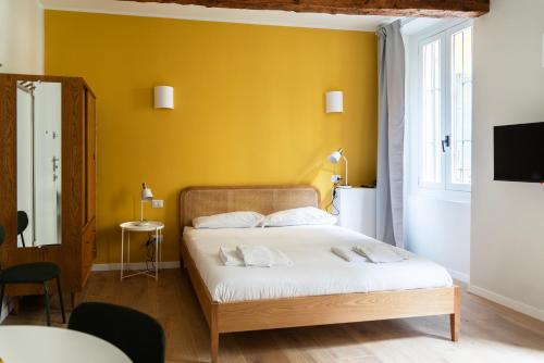 a bedroom with a bed with a yellow wall at Youhosty - Ticinese Suite 2 in Milan