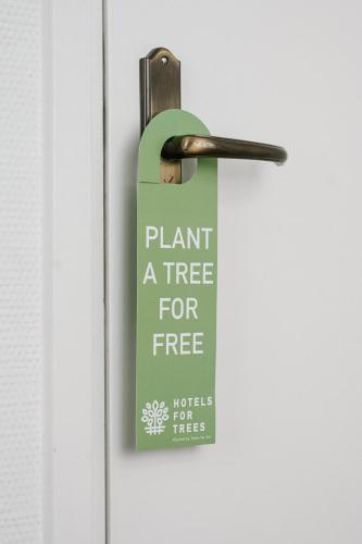 a sign on a door that says plant a tree for free at Stadsherberg de Poshoorn in Maastricht