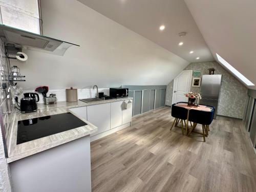 a kitchen with white cabinets and a table in it at Country Haven Comfy & Sleek Apartment in Kildare