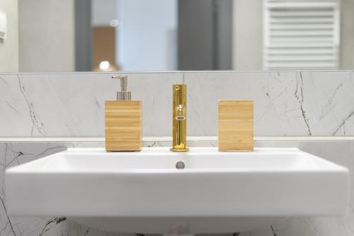 a white bathroom sink with a gold faucet at 04 Gdynia Premium - Apartament Mieszkanie dla 4 osób in Gdynia