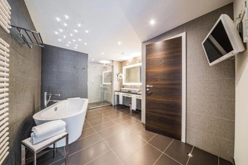 a bathroom with a tub and a sink at Le Clervaux Boutique Hotel & Spa in Clervaux