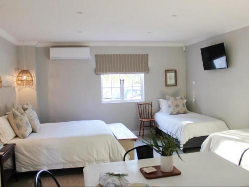 a room with two beds and a table and a tv at Hartshuijs in Beaufort West