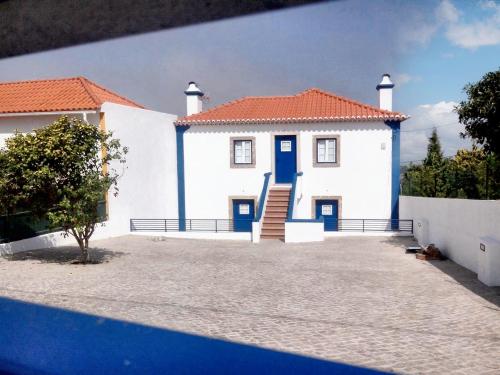 a white house with a blue door and a yard at 3 bedrooms house with city view and terrace at Sintra 3 km away from the beach in Sintra