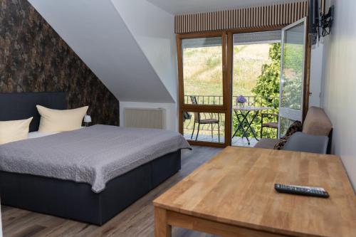 Schlafzimmer mit einem Bett und einem Holztisch in der Unterkunft Hotel Restaurant Moselblick in Wintrich