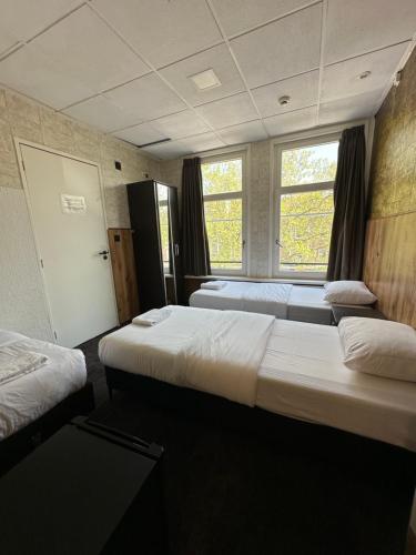 two beds in a room with two windows at Flex-Inn in Rotterdam