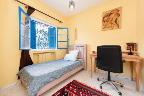 Schlafzimmer mit einem Bett, einem Schreibtisch und einem Stuhl in der Unterkunft Coup de cœur à Sidi Bou Said in Sidi Bou Saïd