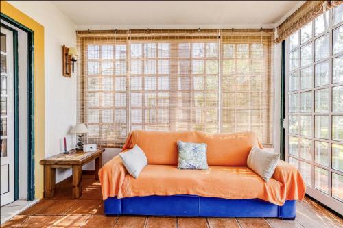 an orange couch in a room with large windows at Casa da Falésia in Melides