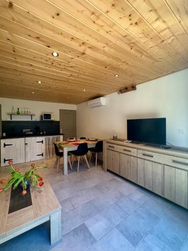 une grande cuisine avec une table et une télévision dans l'établissement Le Gîte des poiriers, à Uzès