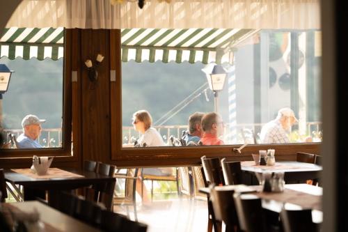 un grupo de personas sentadas en mesas en un restaurante en Hotel Restaurant Moselblick en Wintrich