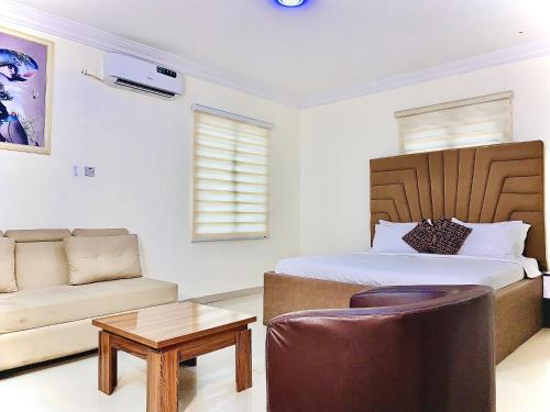 um quarto com uma cama, um sofá e uma mesa em Vintage Classic Lodge em Lagos