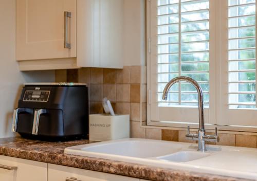 a kitchen counter with a sink and a microwave at Autumn Barn Annexe in Smarden