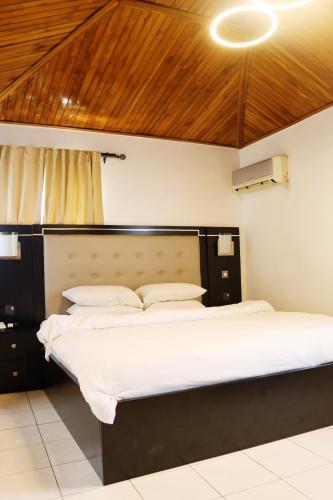 a bedroom with a large bed with a wooden headboard at Cata Apartment Hotel And Spa in Ikeja