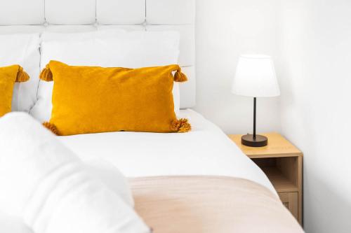 a white bed with yellow pillows and a lamp at 2 Bedroom House - Garden & Parking 2GM - Wifi in Birmingham