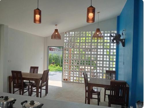 a dining room with a table and chairs and a window at Rapina House in Mai Khao Beach
