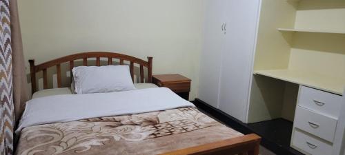 Dormitorio pequeño con cama y vestidor en Cozy Paradise Apartment, en Lilongwe