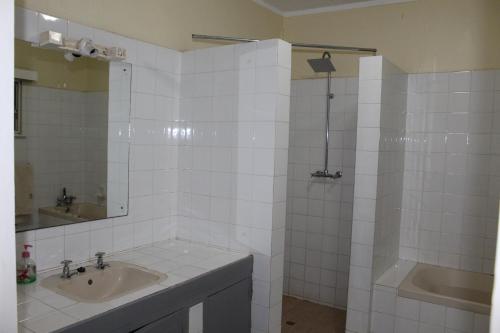 y baño de azulejos blancos con lavabo y ducha. en Cozy Paradise Apartment, en Lilongwe