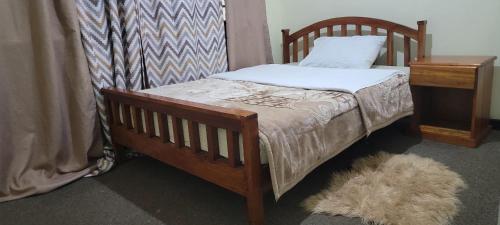 1 dormitorio con cama de madera, almohada y mesa en Cozy Paradise Apartment, en Lilongwe