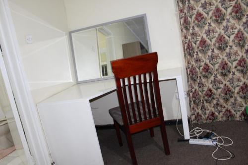 una silla sentada frente a un escritorio con espejo en Cozy Paradise Apartment, en Lilongwe