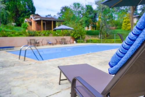 a swimming pool with a table and an umbrella at VELINN Hotel Fazenda Fonte das Hortênsias in Santo Antônio do Pinhal