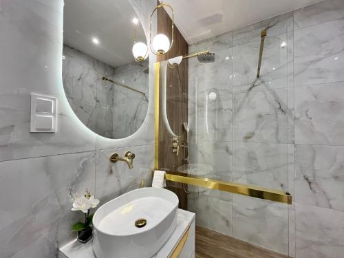 Baño blanco con lavabo y espejo en Apartament Klonova Park 51 en Olecko