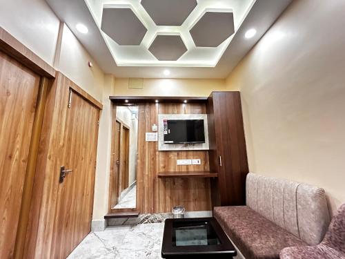 Granotel في kolkata: غرفة معيشة مع أريكة وتلفزيون